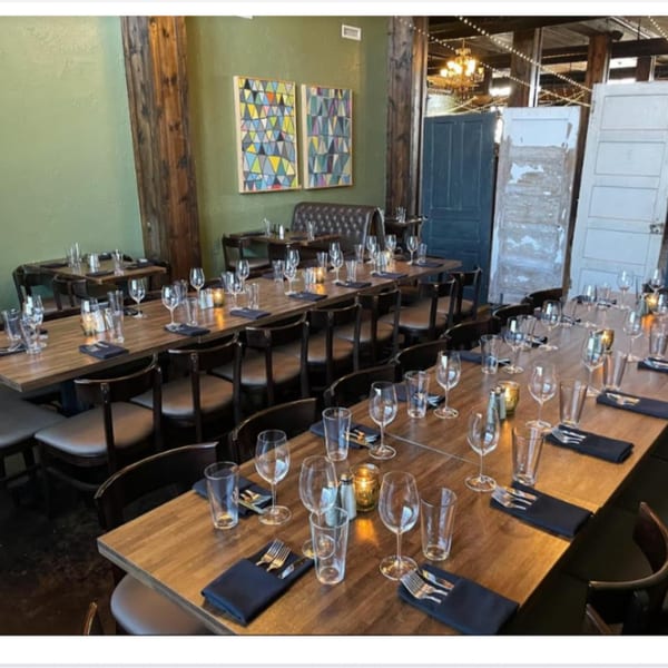 Pignetti's dining room with long wooden tables set with glasses, silverware, and candles, against green walls.
