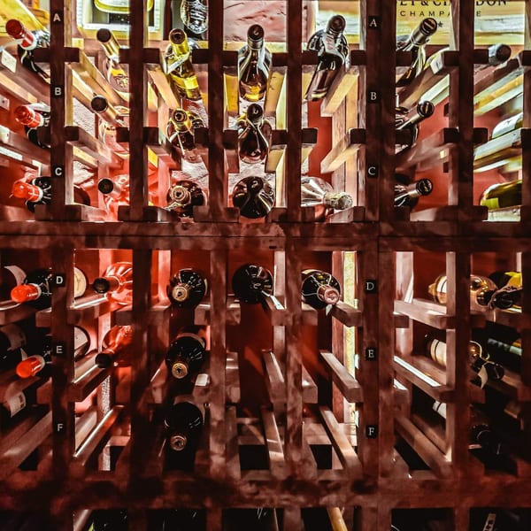 Wine bottles stored in a wooden rack, illuminated by warm red light at Pignetti's.