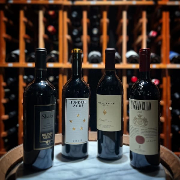 Four bottles of premium red wine, including Tignanello, on a marble surface in a wine cellar.