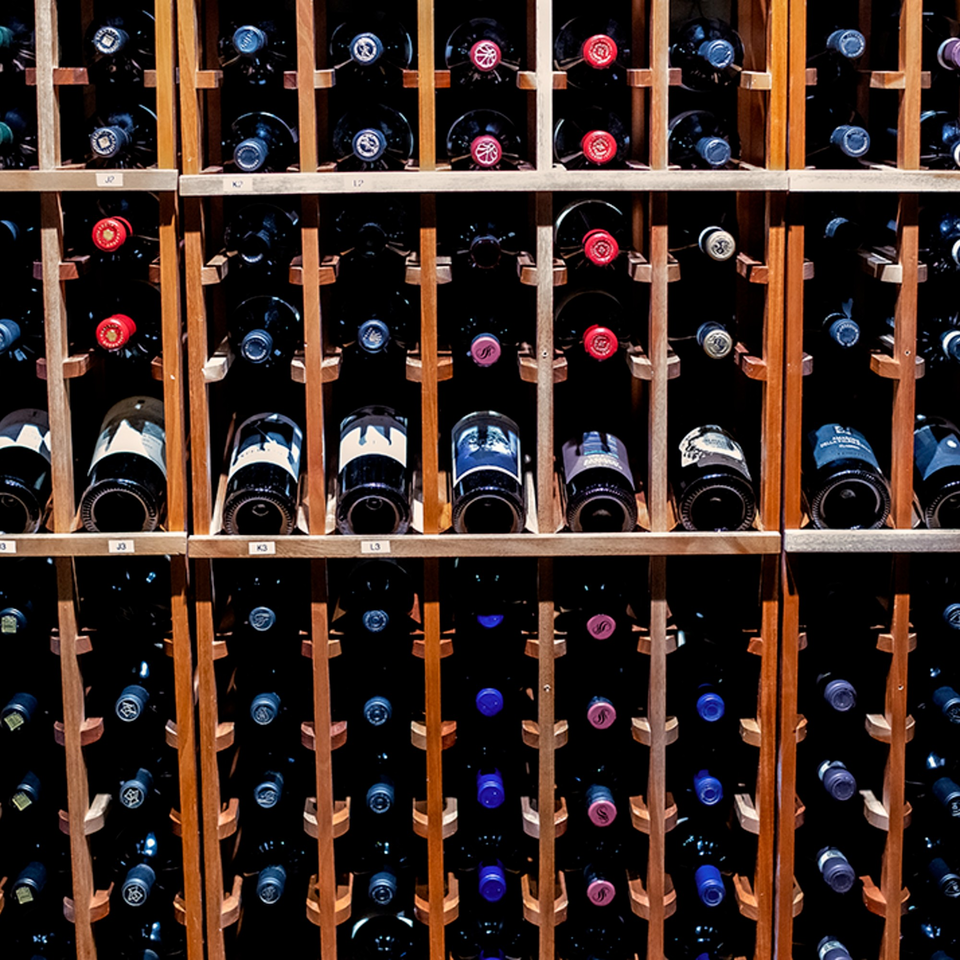A large wooden wine rack filled with numerous bottles of red and white wine.
