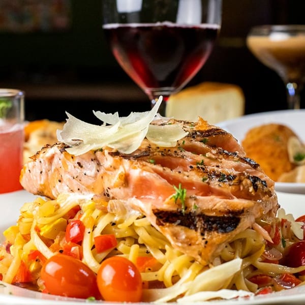 Grilled salmon with shaved parmesan, pasta, cherry tomatoes, and red wine at Pignetti's.