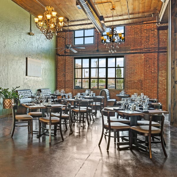 Pignetti's dining room with set tables, exposed brick, green walls, and chandeliers.